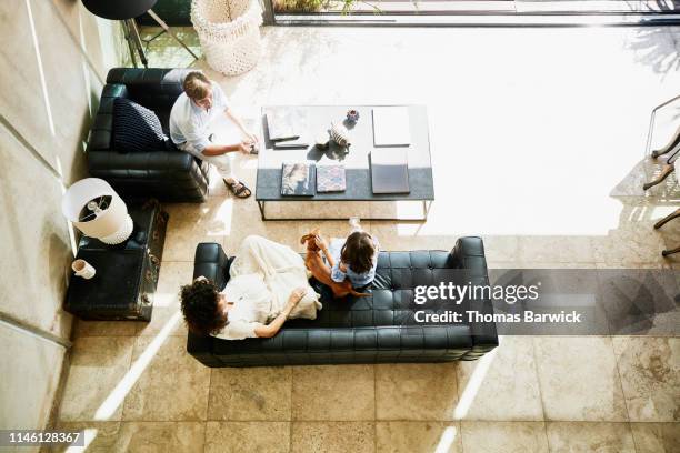 overhead view of mother and father sitting in living room with young daughter - high angle view family stock pictures, royalty-free photos & images