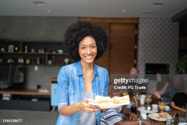 portrait of a young woman holding a plate with sandwiches - sandwich generation stock pictures, royalty-free photos & images