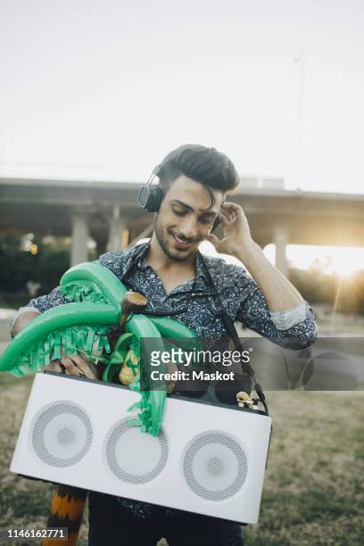 smiling young man with speaker and palm tree balloon enjoying music in festival - arab festival stock pictures, royalty-free photos & images