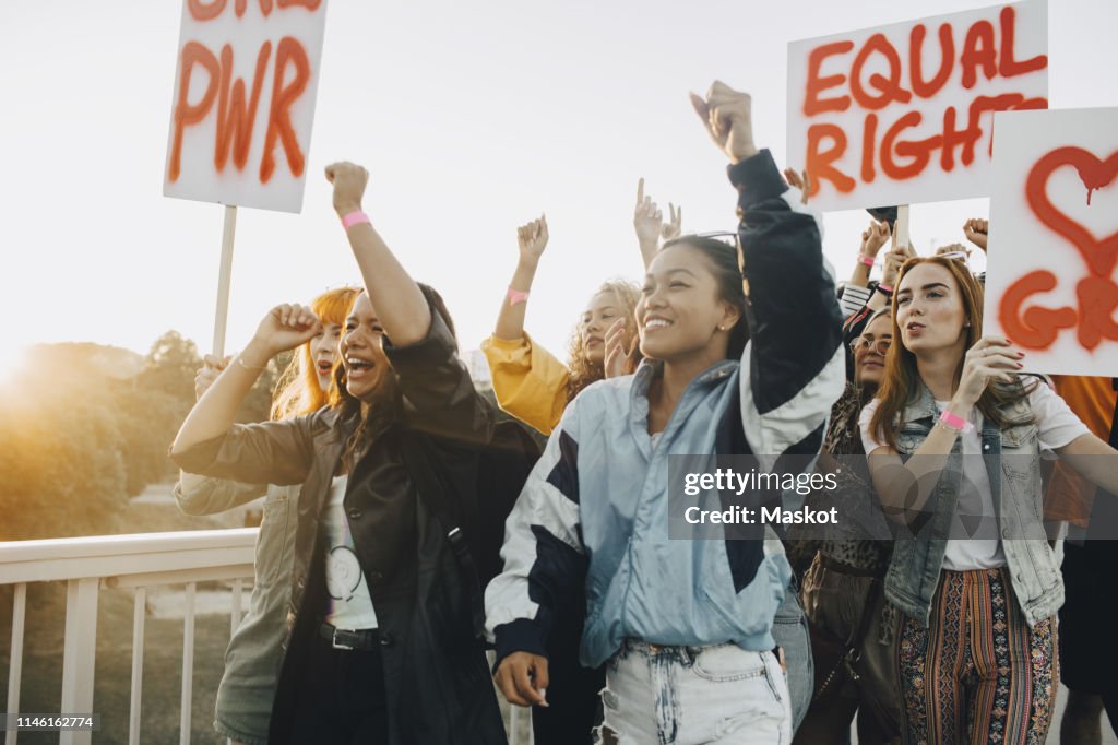 Young women shouting while protesting for equal rights against sky
