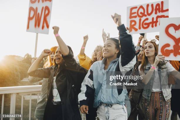 young women shouting while protesting for equal rights against sky - women protest photos et images de collection