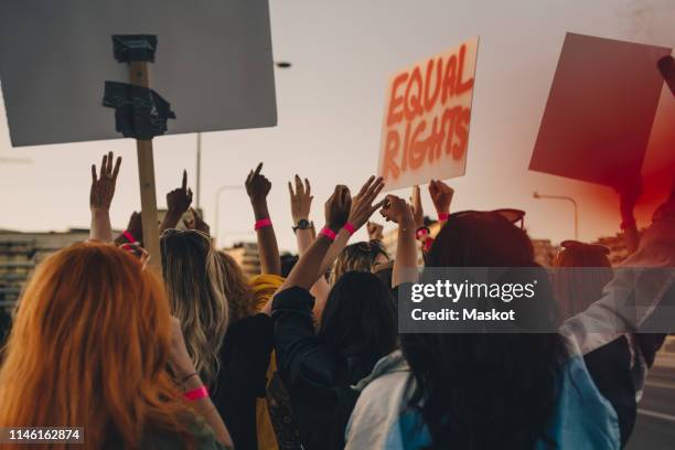 rear view of young women protesting for equal rights while marching in city - asian protestor stock pictures, royalty-free photos & images