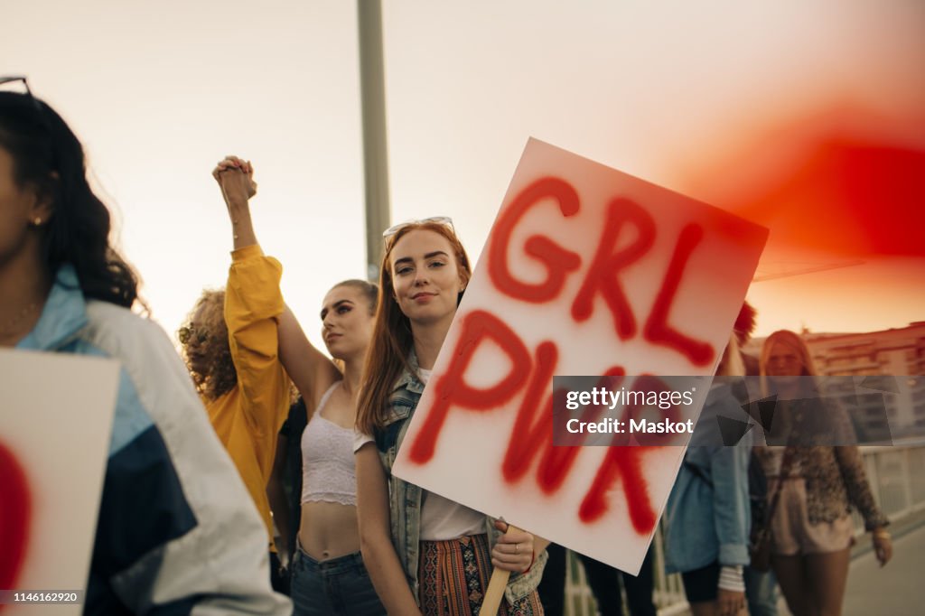 Portrait of women protesting with friends for human rights in city against sky