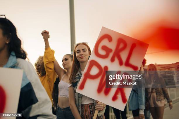 portrait of women protesting with friends for human rights in city against sky - striscione segnale foto e immagini stock