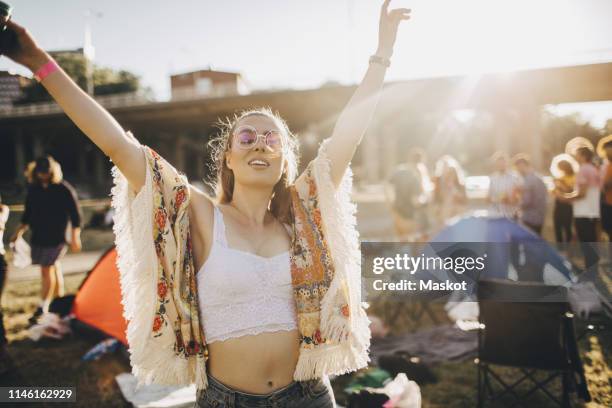 happy young woman with arms raised enjoying at music event during summer - crop top stock pictures, royalty-free photos & images