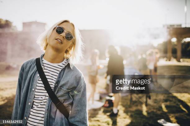 portrait of young confident man wearing sunglasses standing in music festival - coat music festival stock pictures, royalty-free photos & images