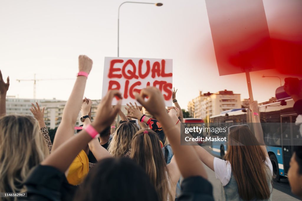 Rear view of women with banners marching for equal rights in city