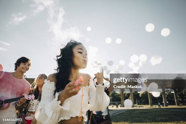 young woman making smoke bubbles while enjoying with friends at music concert - make music day fotografías e imágenes de stock