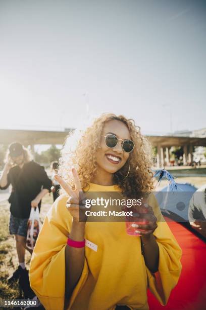 portrait of smiling woman gesturing while enjoying drink in music festival - young woman standing against clear sky stock pictures, royalty-free photos & images