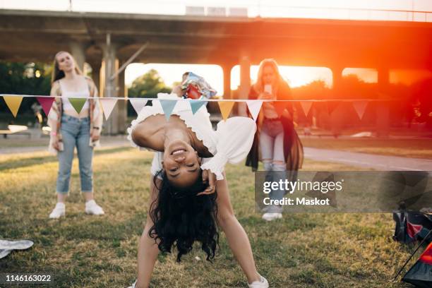 smiling woman performing limbo dance at lawn in music festival - limbo fotografías e imágenes de stock