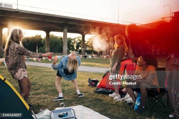 happy friends performing limbo dance on lawn at music festival during summer - limbo stock-fotos und bilder