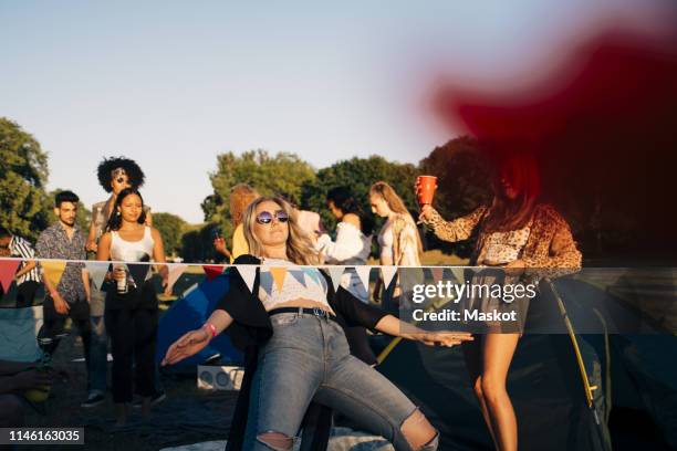 young friends performing limbo dance while camping in music festival - festival camping stock pictures, royalty-free photos & images