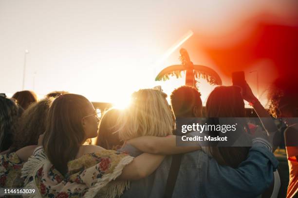 rear view of friends enjoying music festival against sky in summer - crowd anticipation stock pictures, royalty-free photos & images