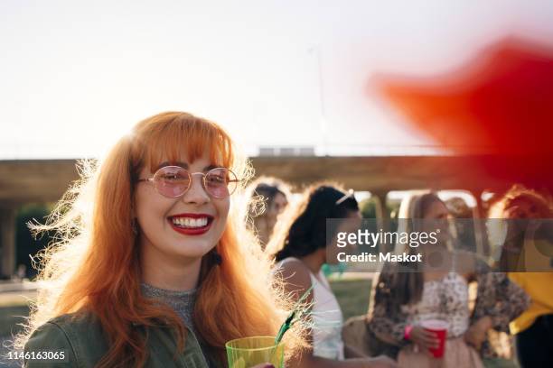 smiling young woman having drink while enjoying with friends during concert - music festival day 4 stockfoto's en -beelden