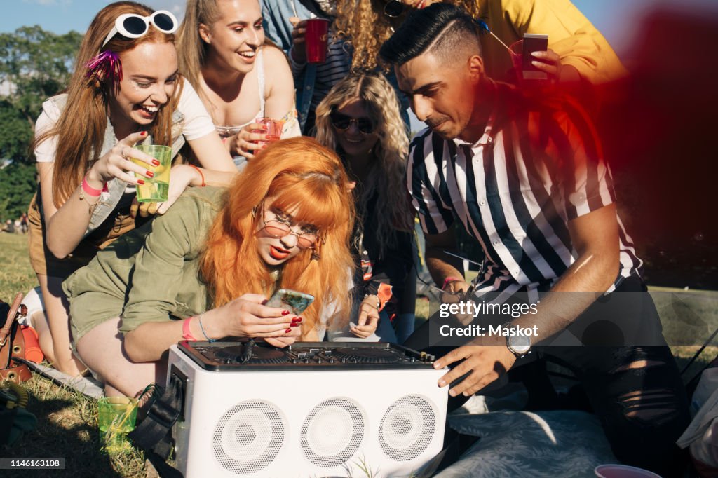 Friends playing music on speaker through smart phone at event