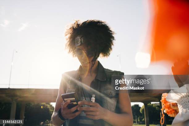 young man with electronic cigarette using mobile phone in summer - world health organisation calls for regulation of ecigarettes stockfoto's en -beelden