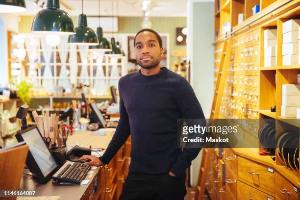Portrait of confident young male owner standing at checkout counter in furniture store