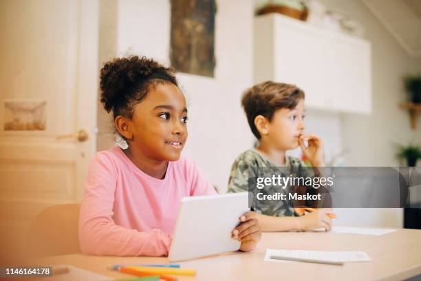 boy learning through digital tablet while sitting with friend at classroom - schulbeginn stock-fotos und bilder