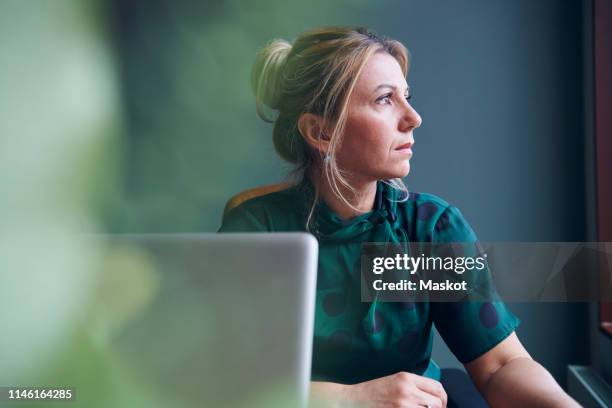 thoughtful businesswoman looking away sitting in board room at office - wonder bildbanksfoton och bilder