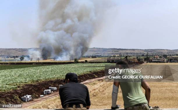 Syrian soldiers look at smoke rising from bombardment during fighting with jihadists in the village of al-Jabiriya in the northern countryside of...