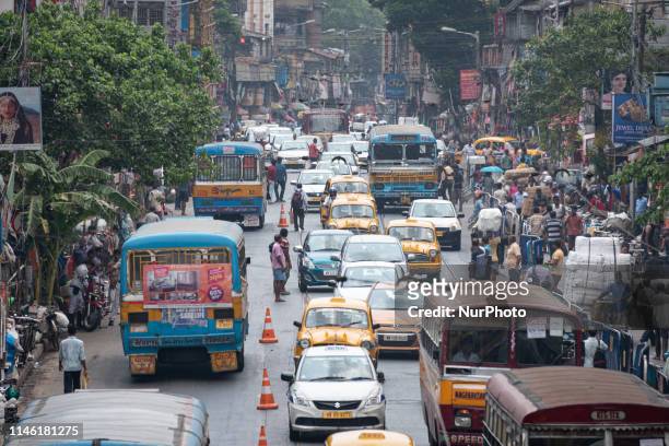 Pedestrians, cars, bicycle carriers and public buses sit in traffic and congestion on a road in the Bara Bazar, Barabazar Market district, in Kolkata...