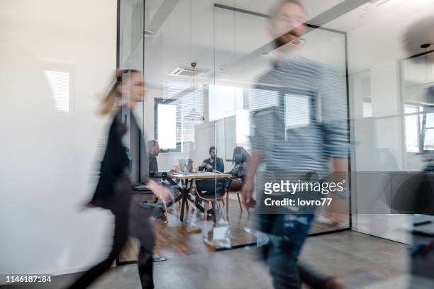 business colleagues walking in the office - blurred office imagens e fotografias de stock