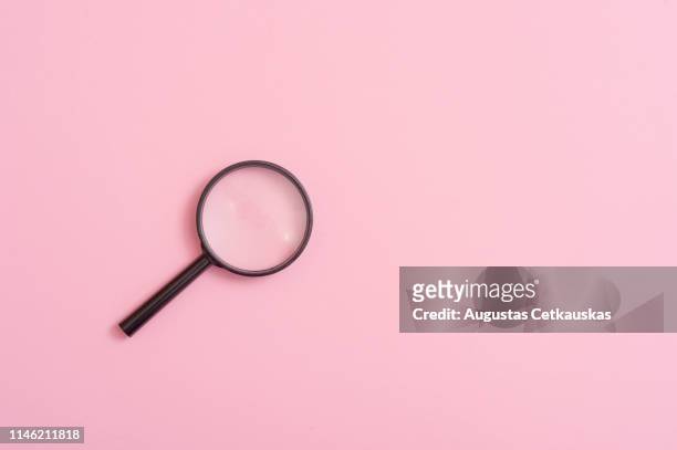 high angle view of magnifying glass over pink background - magnifying glass stock pictures, royalty-free photos & images