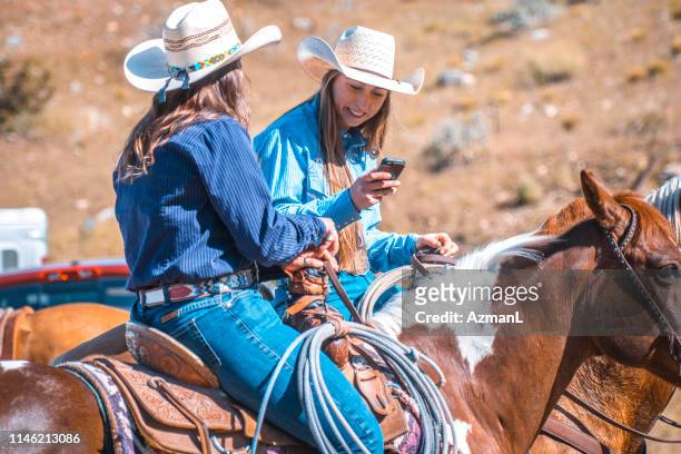 two female western ranchers talk and share phone pics on horseback - paint horse stock pictures, royalty-free photos & images