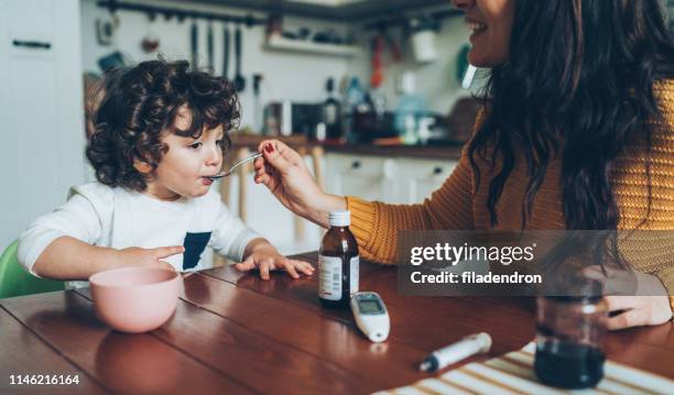 madre che dà sciroppo a suo figlio - sciroppo foto e immagini stock