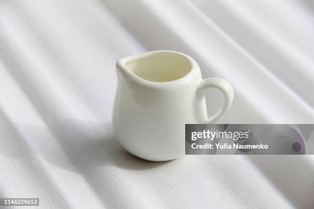 white milk jug for milk on white paper background, corrugated paper - milchkrug stock-fotos und bilder