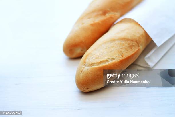 french baguettes, loaves on a light wooden background - wallpaper roll stockfoto's en -beelden