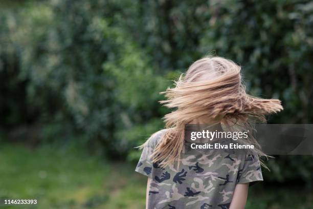 girl (12-13) spinning in a back yard with long fair hair covering her face - bush live stock-fotos und bilder