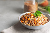 Boiled buckwheat cereal with carrot, parsley and butter in a bowl on a gray background. Traditional Russian dish on gray background with copy space