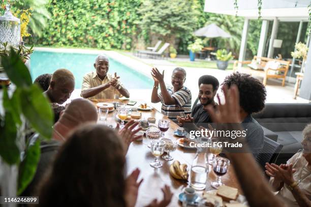 famiglia multigenerazionale che applaude durante la colazione - riunione di famiglia foto e immagini stock