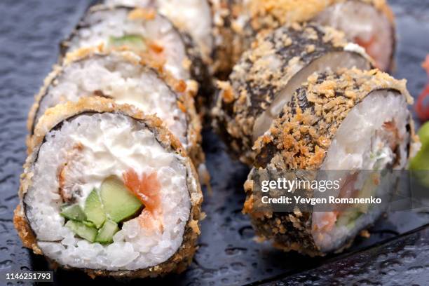 tempura sushi roll with salmon and philadelphia cheese on a black plate - tempura stock pictures, royalty-free photos & images
