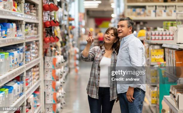 pareja feliz comprando suministros caseros en una tienda - hardware store fotografías e imágenes de stock