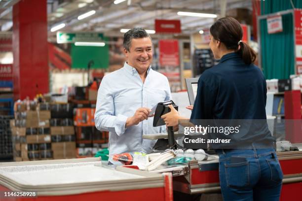 mann zahlt mit karte an der kasse in einem heimwerkerlager - baumarkt stock-fotos und bilder