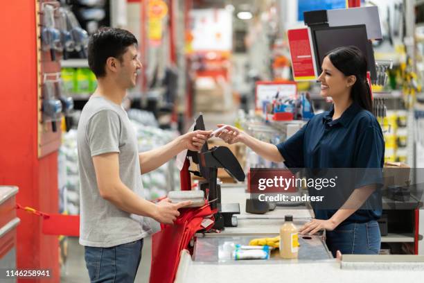 mann zahlt mit karte an der kasse in einem heimwerkerlager - baumarkt stock-fotos und bilder