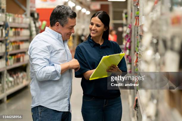 mann kauft in einem baumarkt und spricht mit einer verkäuferin - baumarkt stock-fotos und bilder
