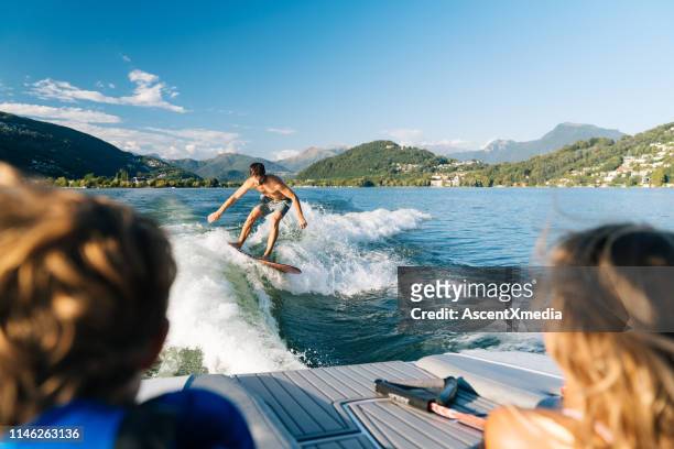 wake surfer rides boat-made wave - boat wake stock pictures, royalty-free photos & images