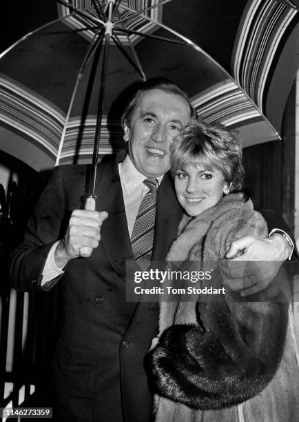 Portrait of married couple British broadcast journalist Sir David Frost and actress Lynne Frederick as they stand under an umbrella, London, England,...