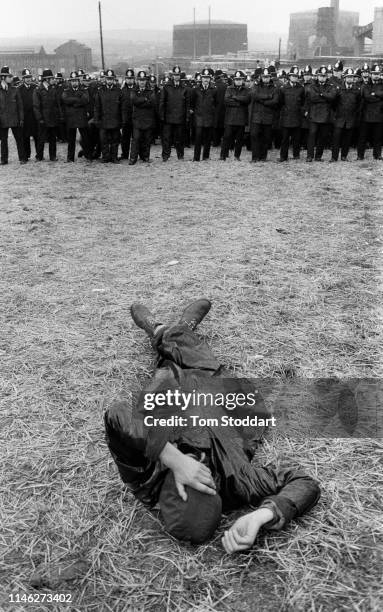 View of a striking miner as he lays on the ground in front of a line of police officers near the Orgreave coking plant, Orgreave , Yorkshire,...