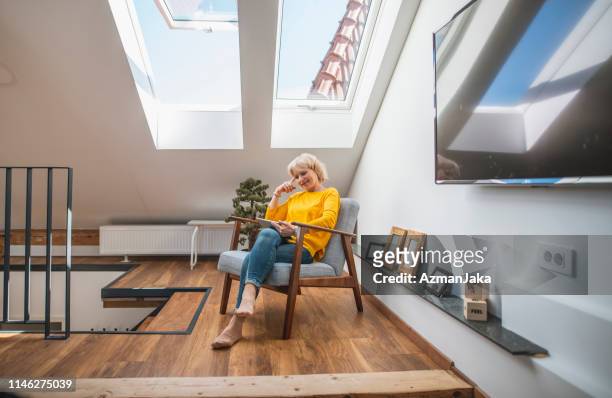 senior woman genieten van alleen tijd met haar digitale tablet in een gezellige nook - nook architecture stockfoto's en -beelden