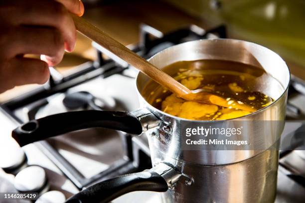high angle close up of person melting wax for candles in saucepan on stove. - melting pot foto e immagini stock
