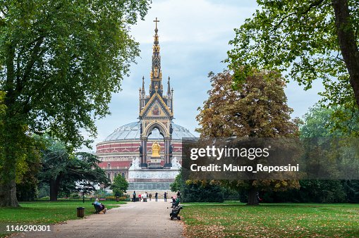 La gente camina y se sienta en los bancos en un parque público al lado del Albert Memorial en Kensington Gardens en Londres, Inglaterra, Reino Unido. La gente camina y se sienta en los bancos en un parque público al lado del Albert Memorial en Kensington Gardens en Londres, Inglaterra, Reino Unido.