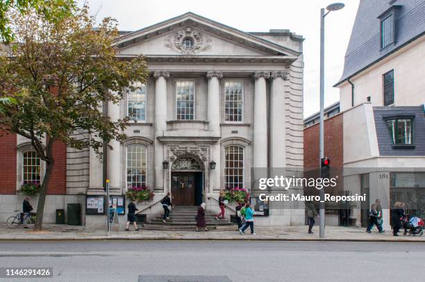 people walking in the street next to the entrance of the chelsea old town hall at london, england, uk. - kensington and chelsea stock pictures, royalty-free photos & images