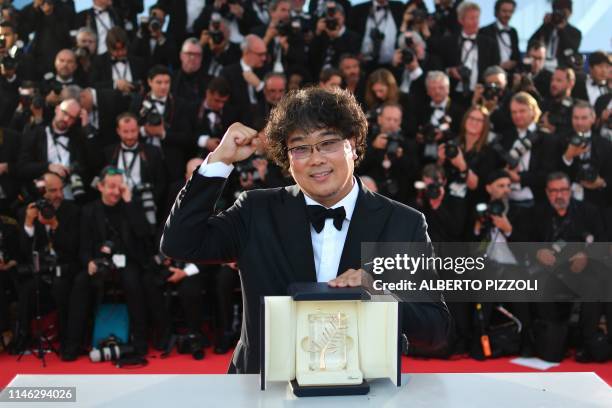 South Korean director Bong Joon-Ho celebrates as he poses during a photocall with his trophy after he won the Palme d'Or for the film "Parasite " on...