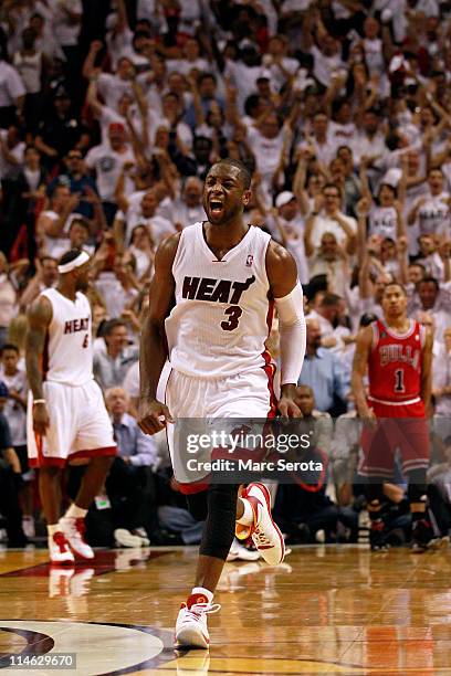 Dwyane Wade of the Miami Heat celebrates as Derrick Rose of the Chicago Bulls looks on dejected in Game Four of the Eastern Conference Finals during...