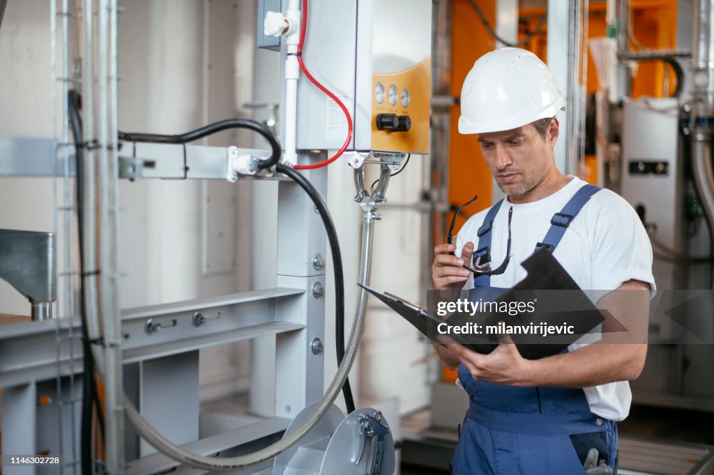 Engineer. Factory worker. Refinery. Handsome factory worker controlling production.