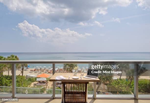 laptop on restaurant balcony table overlooking beach - beach balcony stock pictures, royalty-free photos & images